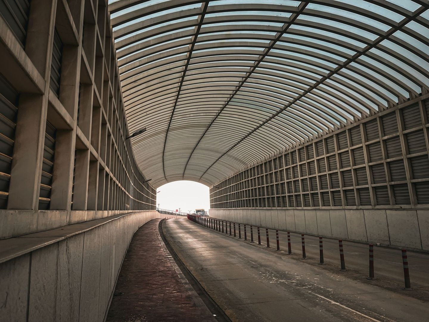 Overdekte landtunnel met gebogen lichtdoorlatend dak en rijbaan