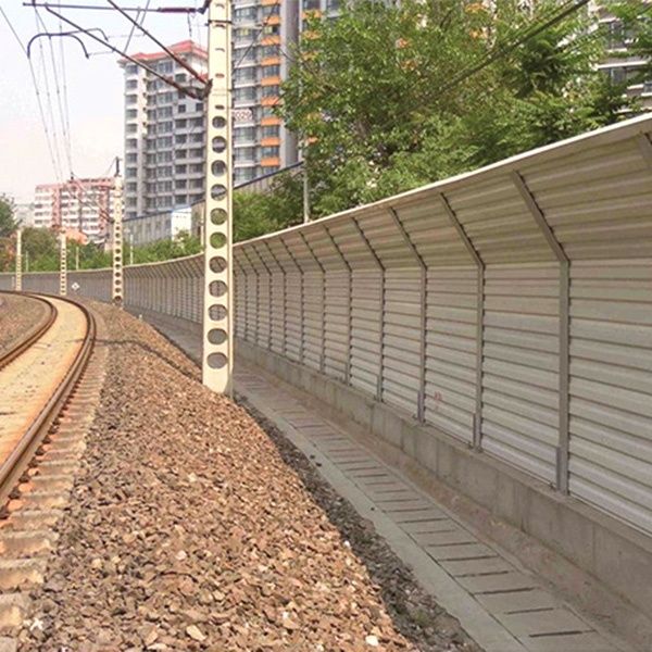 Spoorrails langs een hoge geluidswal in een stedelijke omgeving